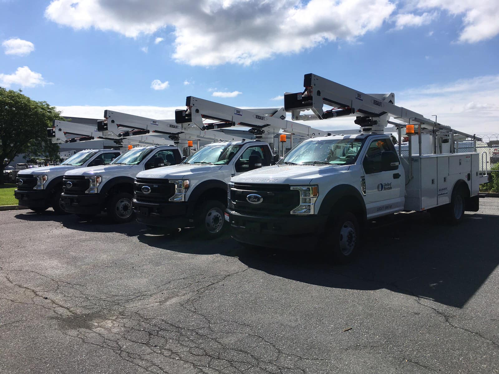 A row of white utility trucks parked in a parking lot.